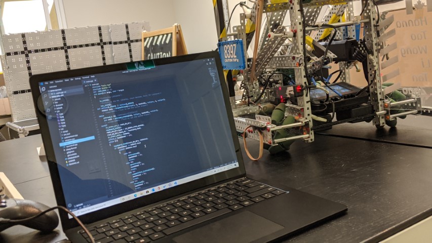 A computer with robot code next to a robot